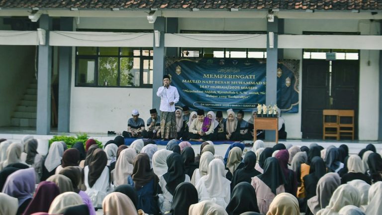 A man speaks to a seated crowd outdoors